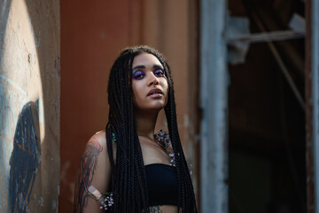 Fototapeta na wymiar Portrait of a young beautiful tattooed girl with box braids hairstyle