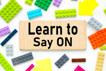 Learn To Say No! text on a wooden plate near the constructor of different colors