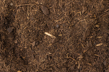 A heap of black brown peat, a natural fertilizer with particles of dead bog plants top view. Peat as a mineral material in natural production close-up