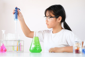 Little girl enjoying to examine the colour chemical in laboratory. Science and education.