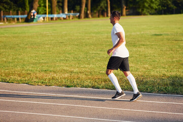 Fototapeta premium Man in sportive unifrom running on the track at daytime