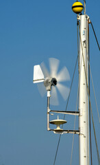 Close up view of a wind powered power generator on top of the mast of a yacht