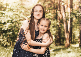 Fototapeta premium two girls sister hugging and smiling on the nature in the summer
