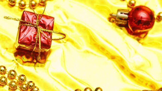 Gift box, shiny gold and red disco balls, sparkling gold glitter on a gold background. New year's baubles, new year's christmas, valentine's day congratulations concept. High quality 4k footage