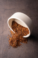 selective focus, natural red leaf tea. brewing in a clay bowl. vertical angle, macro. on a dark background. for menus and cafes