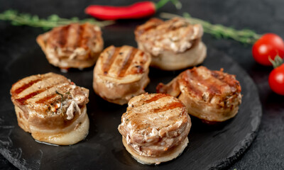Obraz na płótnie Canvas cooked grilled pork tenderloin medallions wrapped in bacon on stone background