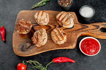 cooked grilled pork tenderloin medallions wrapped in bacon on stone background