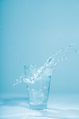 Ice cubes splashing into glass of water, isolated on white