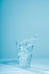 Ice cubes splashing into glass of water, isolated on white
