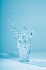 Ice cubes splashing into glass of water, isolated on white