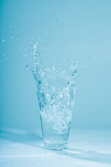 Ice cubes splashing into glass of water, isolated on white