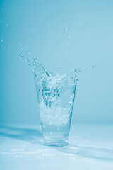 Ice cubes splashing into glass of water, isolated on white