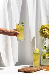 Photo of refreshing summer lemonade cocktail in glass with fresh citrus lime lemon and green mint outdoors with white background