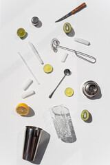 Photo of ingridients for refreshing summer lemonade cocktail  with fresh citrus lime lemon and green mint and cocktail bar tools outdoors with white background flat lay style
