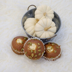 A peaceful setting of cupcakes and gourds on a bedroom serving table.