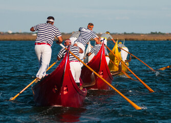 Beautiful shot of males from back in striped shirts riding gondolas in Venice, Italy © Simone Padovani/Wirestock