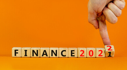 2022 finance and new year symbol. Businessman turns wooden cubes, changes words 'finance 2021' to 'finance 2022'. Beautiful orange background, copy space. Business, 2022 finance and new year concept.