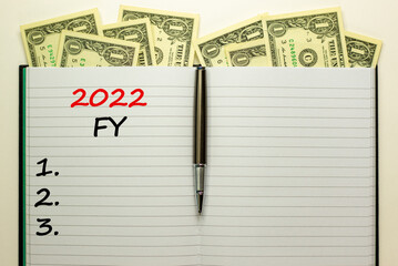 2022 FY fiscal new year symbol. White note with words 2022 FY fiscal year on beautiful white background, dollar bills, metallic pen. Business and 2022 FY fiscal new year concept.