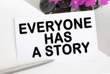 EVERYONE HAS A STORY .Top view of open blank on white background with flowers