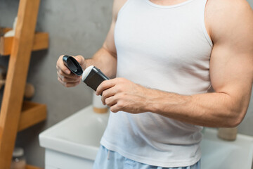 cropped view of man opening antiperspirant stick in bathroom