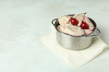 Pot with pierogi with cherry on white textured table
