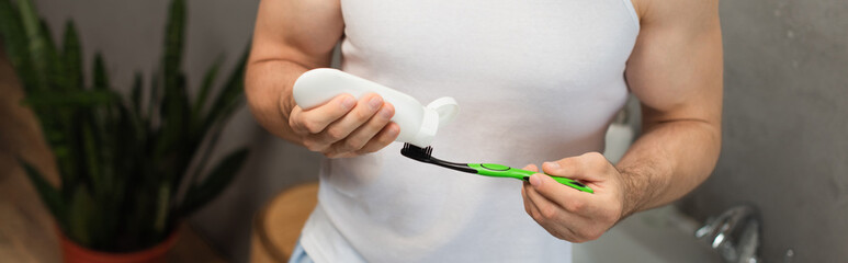 partial view of man applying toothpaste on toothbrush, banner