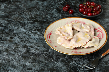Plate with pierogi with cherry on black smokey background