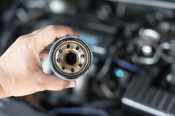 Close up hand a man hold old oil filter for car maintenance concept in engine room background