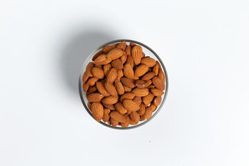 Fototapeta na wymiar Almonds in a glass cup on a white background. Close-up.