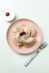 Plate with pierogi with cherry on white background