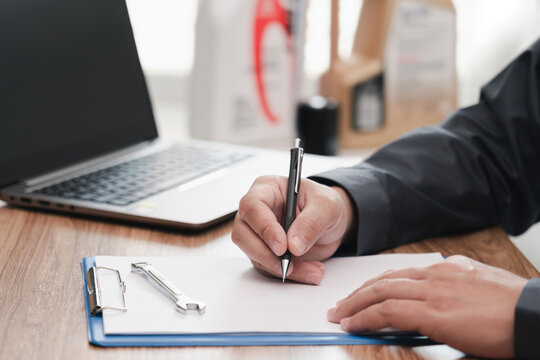 Car service staff use laptop computer check the car's mileage check cycle to change the oil and check list on the white paper clip board file : service concept