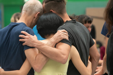 3 dancers hugs in contact improvisation performance against a background of jam performance...