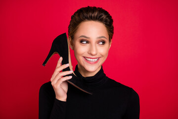 Photo of young happy positive funky woman look empty space hold shoe talk call isolated on red...