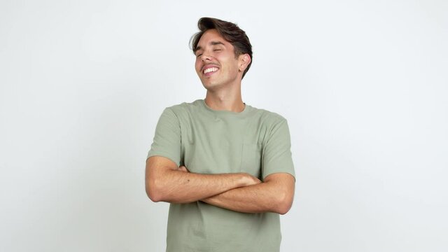 Young man posing with arms at hip and laughing over isolated background
