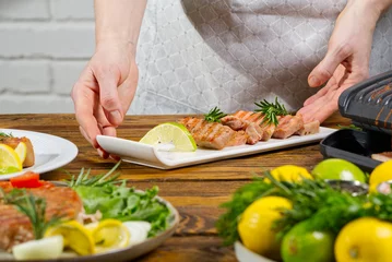 Fotobehang Chef hands decorating sliced fried yellow tuna fish with vegetables. blue tuna steak © Ilja
