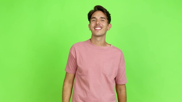 Young man points finger at you with a confident expression over isolated background. Green screen chroma key