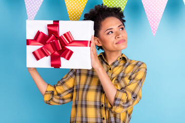 Photo of young black girl curious shake gift box dream think look empty space isolated over blue color background