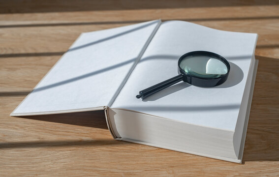 Magnifying Lens With Open Thick Book On Wood Desk With Day Light. Start From Scratch Concept.