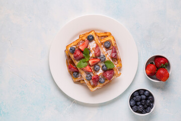 Fototapeta na wymiar Belgian waffles with strawberries, blueberries and syrup, homemade healthy breakfast