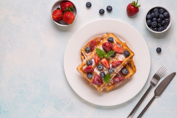 Belgian waffles with strawberries, blueberries and syrup, homemade healthy breakfast
