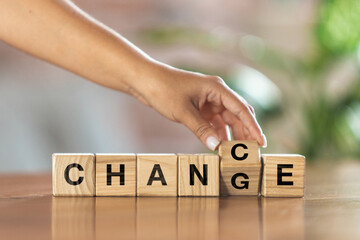 Wooden cubes, blocks with word Change in female hand. Conceptual image about human rights, education, social issues, mental health, education and personal development.