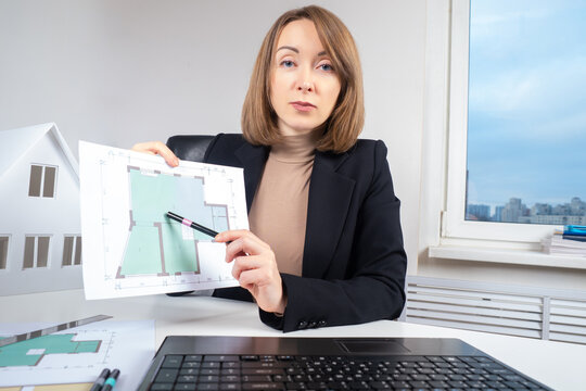 Woman shows the plan of the apartment. Girl develops a construction project remotely. A female architect is engaged in the project of a cottage. The engineer prepares drawings of the future house.