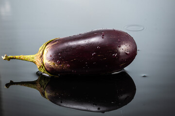 fresh eggplant on dark gray background with water splashes