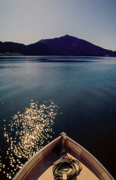 Bow of boat with rope and anchor on deck, moving through calm water