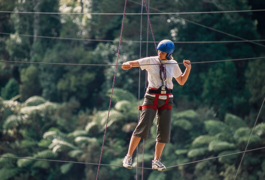 Woman manoeuvring along suspended ropes on outdoor ropes course