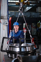 A worker in overalls and a hard hat moves a large-diameter bearing. Bearing plant. Large diameter...