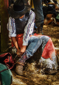 Young male rider fixing his boots prepareing for his round at Rodeo