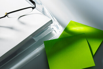 Spectacles sitting on blank paper next to adhesive notes
