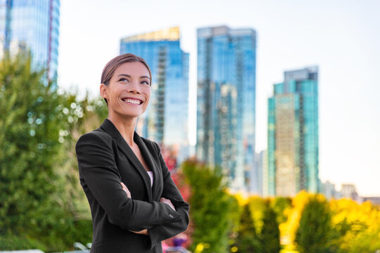 Happy businesswoman portrait of young Asian executive wearing professional suit confident outside office buildings looking up aspirational. Ethnically diverse successful woman at her job.