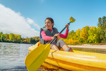Naklejka premium Kayak fun water sports on river in Laurentians, Quebec, Canada. Summer travel destination. Happy Asian woman kayaker kayaking in lake.